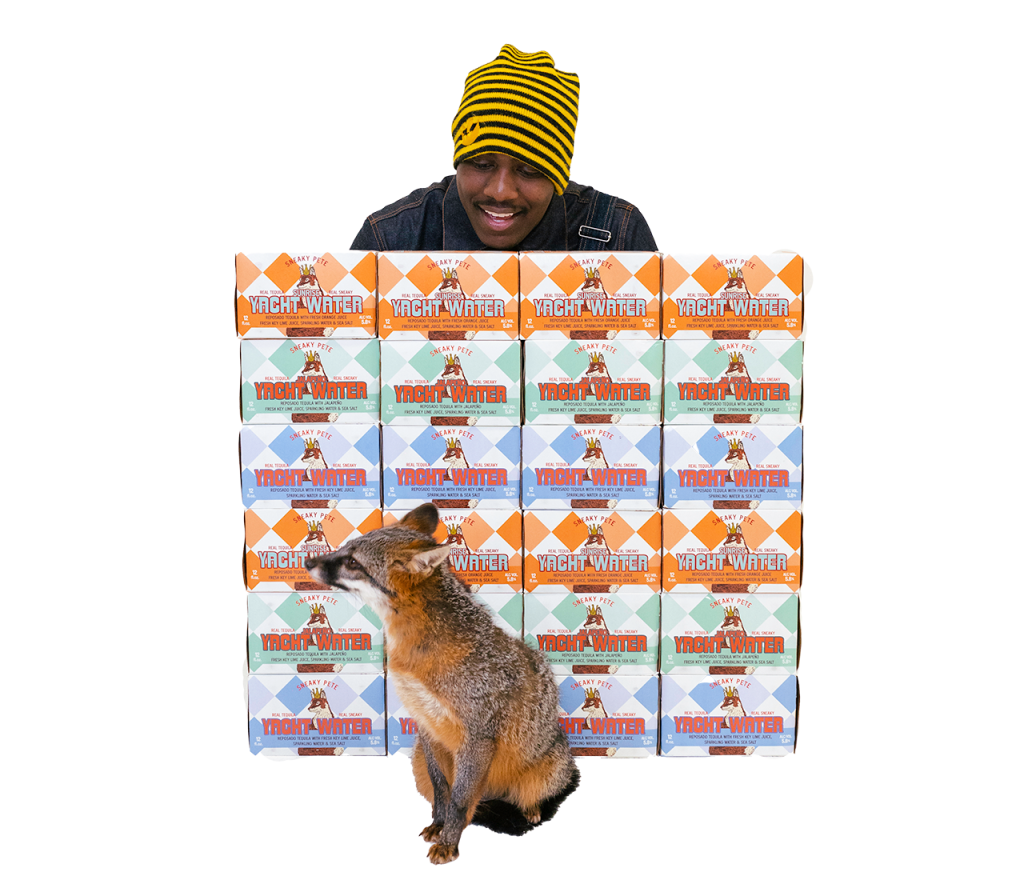 Press Photo - Lil Yachty behind a wall of Yacht Water cases looking down on a red fox