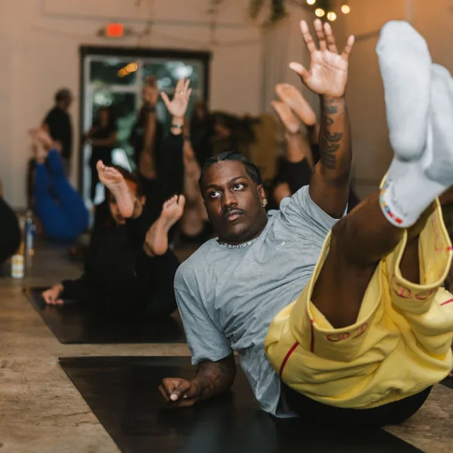 Guests holding a Pilates leg raise at Yacht Club with Kinfolk Pilates